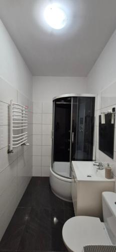 a white bathroom with a sink and a tub at Apartament Opole Przylesie Self Check-in in Opole