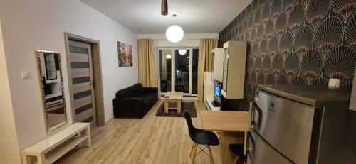 a living room with a kitchen and a living room with a couch at Apartament Opole Przylesie Self Check-in in Opole