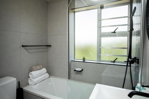 baño con bañera, ventana y lavamanos en Two-bed Apartment on Big Bay Beach Club,Cape Town, en Ciudad del Cabo