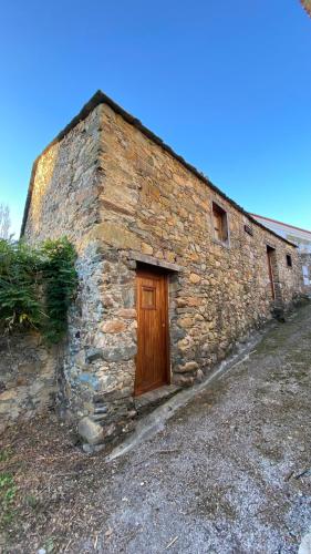 an old stone building with a wooden door at LouzaNook - Casa do Moinho in Lousã
