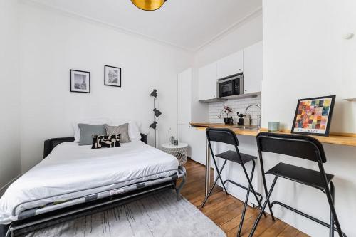 une chambre avec un lit et deux chaises noires dans l'établissement Studio Tolbiac, à Paris