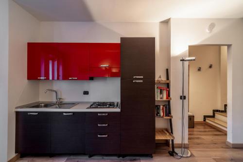 een keuken met rode kasten en een spoelbak bij Outdoor Apartments - Studiò11Centro in Aosta