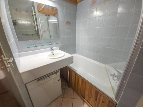 une salle de bain avec un lavabo, une baignoire et un miroir dans l'établissement Résidence Combes - Appartement 3 personnes avec vue panoramique MAE-5764, aux Menuires