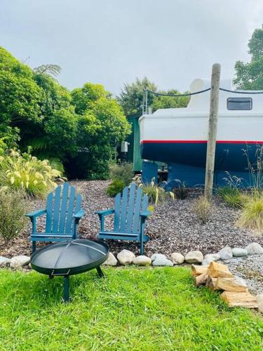 two chairs and a table in a yard with a boat at Tata Sails - 200m walk to beach in Tata Beach