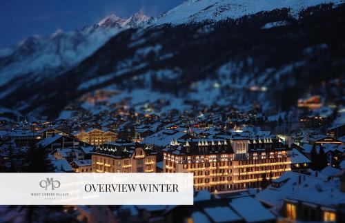 a view of a city with snow covered mountains at Mont Cervin Palace in Zermatt