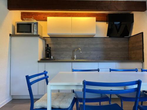 une cuisine avec une table blanche et des chaises bleues dans l'établissement Haut perché - Duplex familial confortable et rénové bien situé, à Briançon