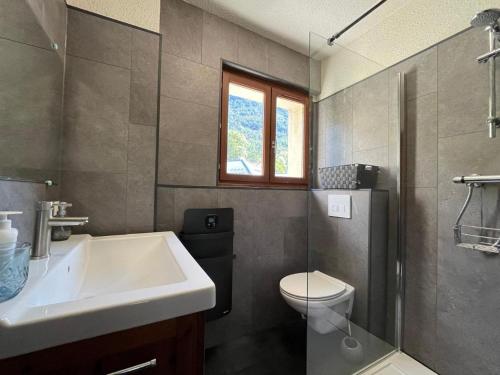 une salle de bain avec un lavabo et des toilettes et une fenêtre dans l'établissement Haut perché - Duplex familial confortable et rénové bien situé, à Briançon