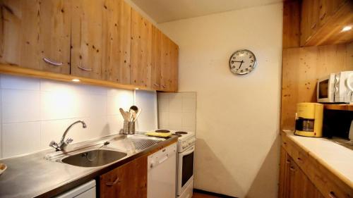 une cuisine avec un évier et une horloge murale dans l'établissement Résidence Diamant - 3 Pièces pour 7 Personnes 361, à Aime La Plagne