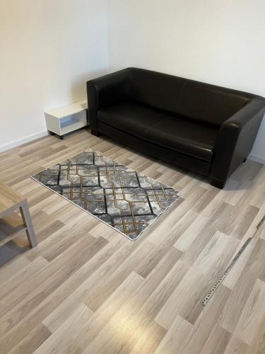 - un canapé noir dans le salon doté de parquet dans l'établissement Tranquilliter en bord de loire, à Roanne