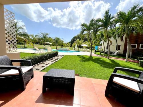 a patio with two chairs and a pool with palm trees at Crea experiencias inolvidables Mini studio in Paraíso