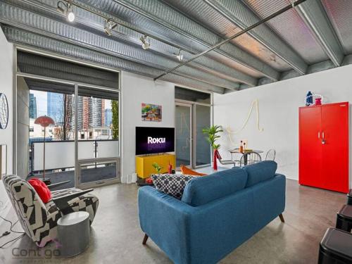 a living room with a blue couch and a tv at Urban Pop Loft, Near ICE District, UG Parking in Edmonton
