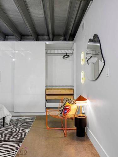 a living room with a chair and a mirror at Urban Pop Loft, Near ICE District, UG Parking in Edmonton