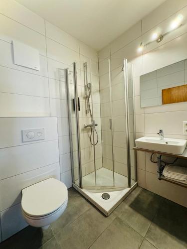a bathroom with a shower and a toilet and a sink at Landgasthof Hotel Zwickl in Deggendorf