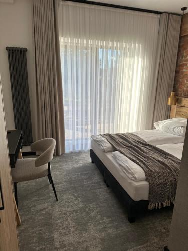 a bedroom with a bed and a chair and a window at Kama Lama in Zakopane