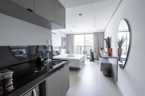 a kitchen with a sink and a room with a bed at Way Tambaú #H6 - Triplo Deluxe por Carpediem in João Pessoa