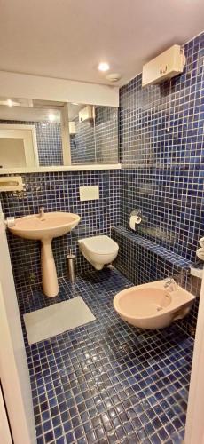 La salle de bains est pourvue de carrelage bleu, de toilettes et d'un lavabo. dans l'établissement Home Sweet Home Champs Elysées Berri, à Paris