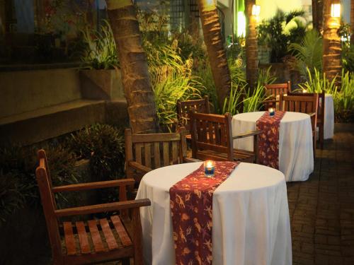 a row of tables with white table cloths and candles at Aryaduta Manado in Manado