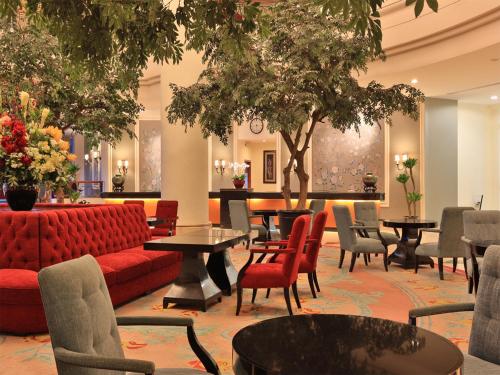 a lobby with a red couch and tables and chairs at Aryaduta Manado in Manado