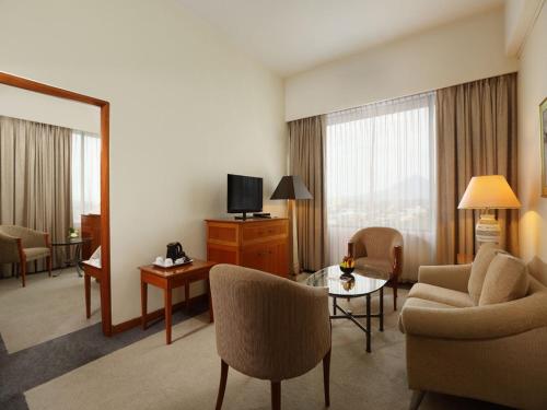 a hotel room with a living area with a television at Aryaduta Manado in Manado