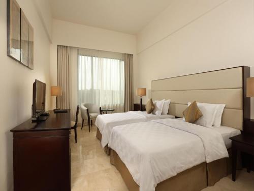 a hotel room with two beds and a television at Aryaduta Manado in Manado