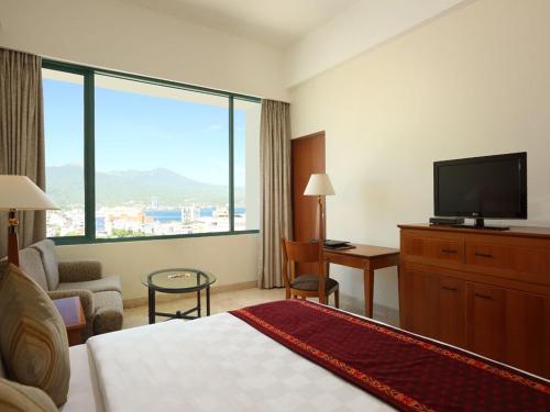 a hotel room with a bed and a flat screen tv at Aryaduta Manado in Manado