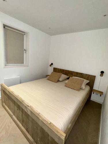 a bedroom with a large bed with a wooden headboard at Wellness Chalet Hellendoorn met Hot tub en Sauna in Haarle