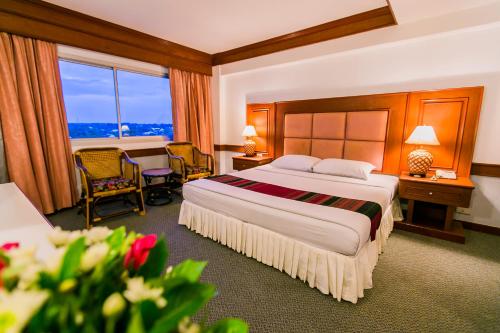 ein Hotelzimmer mit einem Bett, einem Tisch und Stühlen in der Unterkunft Raya Grand Hotel in Nakhon Ratchasima