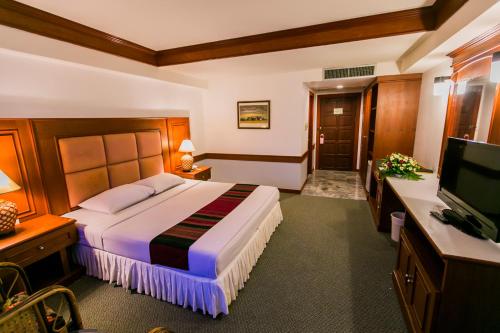 ein Hotelzimmer mit einem Bett und einem TV in der Unterkunft Raya Grand Hotel in Nakhon Ratchasima