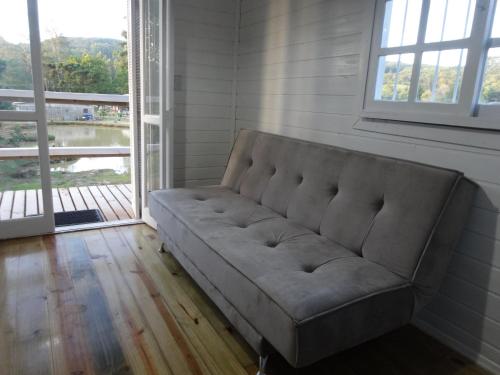 a couch sitting in a room with a large window at Pousada Rancho do Lago in Osório