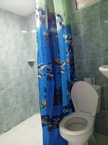 a bathroom with a toilet and a blue shower curtain at Sharly House in Cartagena de Indias