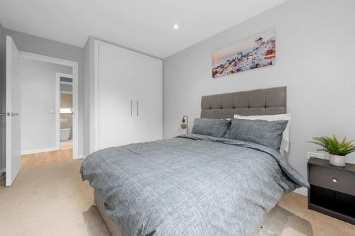 a bedroom with a bed with a gray blanket at Manchester Haven Stylish Modern Apartment in Manchester