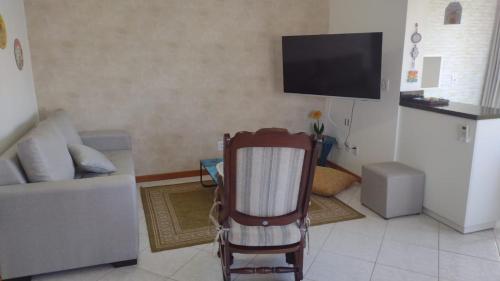 un soggiorno con sedia e TV a schermo piatto di APARTAMENTO SOLAR DA PRAÇA, Aconchegante e Climatizado a Torres