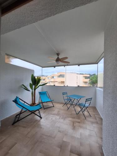 un salon avec des chaises bleues et un ventilateur de plafond dans l'établissement Malyna, à Mandelieu-la-Napoule