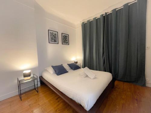 une chambre avec un grand lit blanc avec des oreillers bleus dans l'établissement Le Minck, à Calais