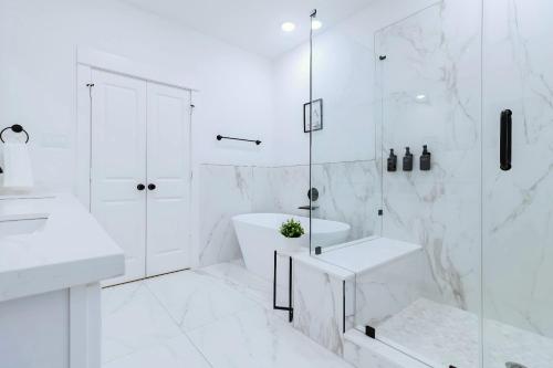 a white bathroom with a tub shower and a sink at Private Rooftop in Houston's Downtown! Pizza Oven and Skyline Views in Houston