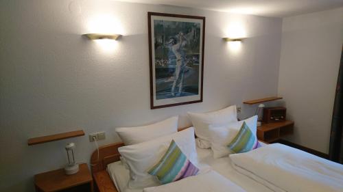 a bedroom with a bed with white sheets and pillows at Pension Landhaus Fischer in Maßweiler