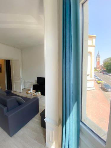 un salon avec un canapé et une grande fenêtre dans l'établissement Le Saint Pierre, à Calais