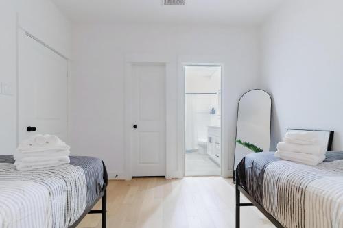 a white room with two beds and a mirror at Private Rooftop in Houston's Downtown! Pizza Oven and Skyline Views in Houston