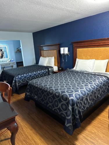 two beds in a hotel room with blue walls at Tanglewood Motel in Frederick