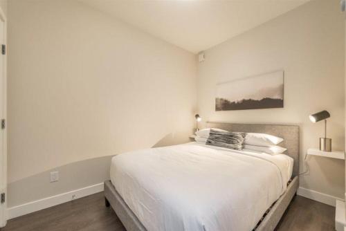a white bedroom with a large white bed in it at Modern Old Town Suite With Private Balcony in Victoria