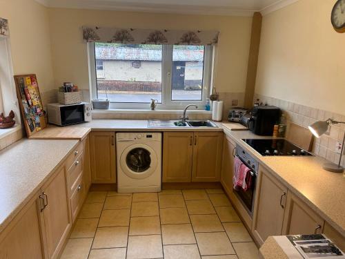 a kitchen with a washing machine and a window at Chestnut Lodge Annex in Bridgend