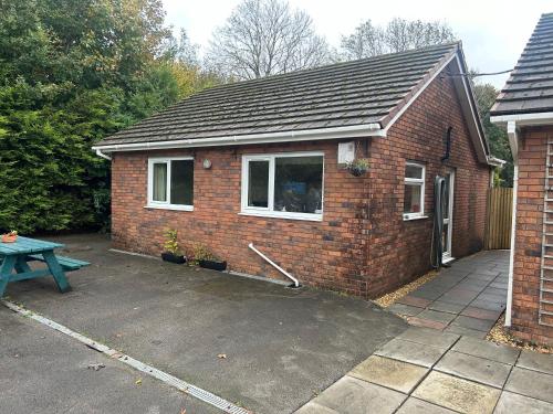 a small brick house with a picnic table in front of it at Chestnut Lodge Annex in Bridgend