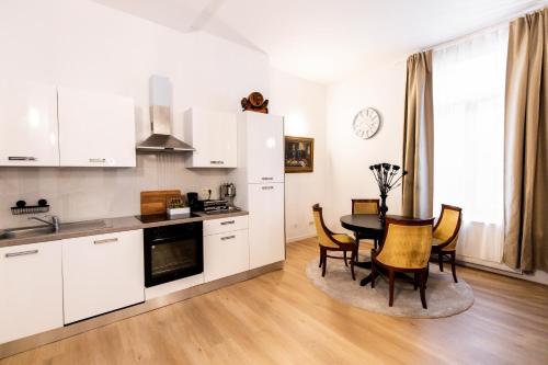 a kitchen with white cabinets and a table and chairs at Gotha Aparthotel in Brussels