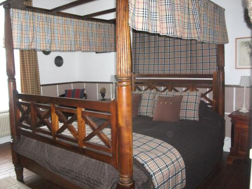 - un lit à baldaquin avec un cadre en bois dans une chambre dans l'établissement La Mirabelle, à Cornimont