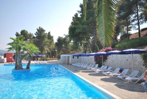 - une piscine avec des chaises longues et des parasols dans l'établissement Villaggio Santo Stefano, à Vieste