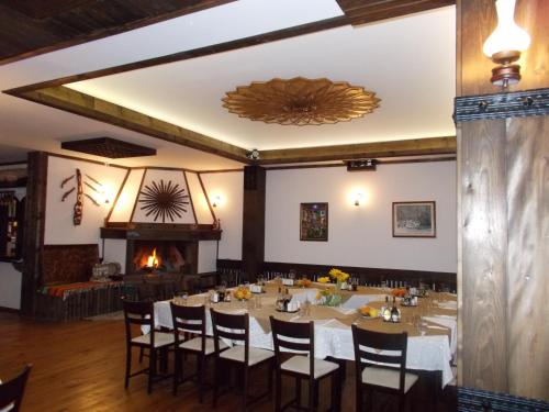 a dining room with a table and chairs and a fireplace at Panorama Family Hotel in Zlatograd