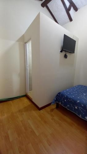 una piccola stanza con un letto e una tv di MANDALA HOSTAL CUENCA a Cuenca