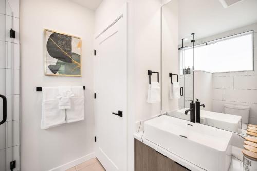 a white bathroom with a sink and a mirror at Brand New Eastlake Studio - SLU UW Shops & Eats in Seattle