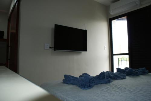 a bedroom with a bed with a television on the wall at Flat Sirena - São Vicente in São Vicente