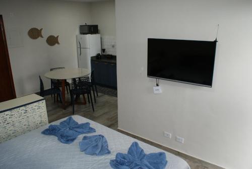 a living room with a television and a bed with blue sheets at Flat Sirena - São Vicente in São Vicente